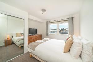a bedroom with a large bed and a television at Quayside Apartment in Dundee