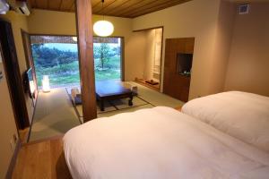 a bedroom with two beds and a table and a window at Ryokan Konomama in Minami Aso +35 photos