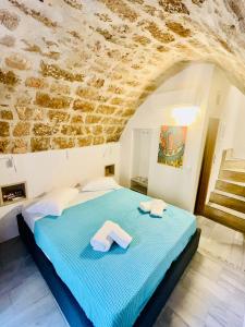 - une chambre avec un lit et un mur en pierre dans l'établissement Vecchia Casa kamara, à Monemvasia