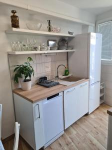 La cuisine est équipée de placards blancs et d'un réfrigérateur blanc. dans l'établissement Apartman Kale, à Šibenik