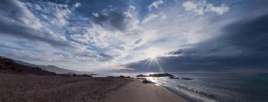 a view of a beach with the sun in the sky at Huelintown in Málaga