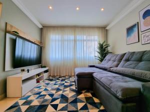 a living room with a couch and a flat screen tv at Apartamento moderno e aconchegante. Pé na areia!!! in Guarujá