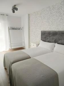 1 dormitorio con 2 camas y pared en Second Home Arzúa apartamentos, en Arzúa