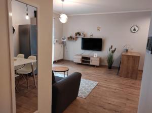 sala de estar con TV y mesa de comedor en Apartament Tuwima Park en Ełk