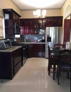 cocina con armarios de madera, mesa y nevera en The Ansen Place, en Belmopan