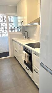 a white kitchen with a sink and a stove at Modern apartment with parking 2 min from the beach in Calella de Palafrugell