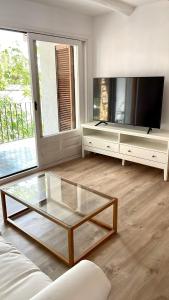 a living room with a glass coffee table in front of a tv at Modern apartment with parking 2 min from the beach in Calella de Palafrugell