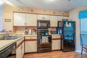 a kitchen with a black refrigerator and a sink at Lovely 2-bedroom condo with pool in Myrtle Beach
