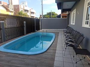 ボンビーニャスにあるCASA ARMANI 50 metros DA PRAIA MARISCAL BOMBINHASのパティオ(椅子付)のスイミングプールを利用できます。