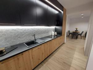 eine Küche mit schwarzen Schränken, einer Spüle und einem Tisch in der Unterkunft ŁośHouse in Bytów