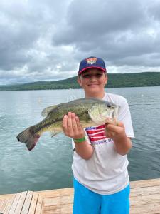 a boy holding a fish in front of a body of water at Lake View Motel in Cooperstown