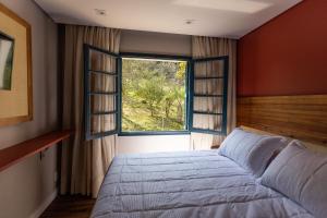 a bedroom with a bed and a large window at Umani Pousada in Bento Gonçalves