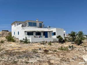 a white house in the middle of a field at Dar Nouha : un appartement sur l'océan in Wassane