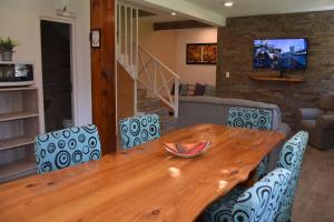 una mesa de madera con sillas azules y una sala de estar. en Cabanas Luces el Bosque en Mar de las Pampas