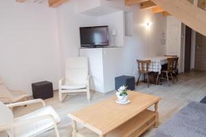 a living room with a table and a tv at Suites Conviviales la Vignette in Benfeld