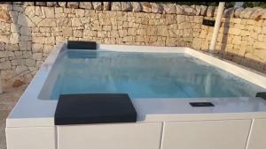 a swimming pool with two stools in front of a stone wall at TRULLI TESORO in Cisternino