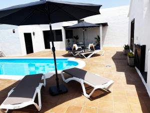 a patio with two chairs and an umbrella next to a pool at Nazaret Villa with heated pool in Nazaret