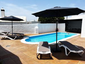 Nazaret Villa with heated pool في Nazaret: مسبح مع كرسيين للصالة ومظلة