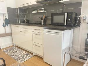 - une cuisine avec un comptoir blanc et un four micro-ondes dans l'établissement Paris 16 Victor Hugo superbe studio, à Paris