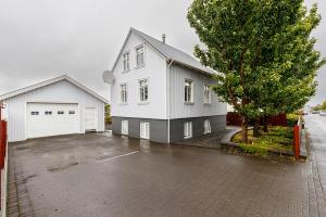 a white house with a garage and a tree at V13 Guesthouse in Keflavík