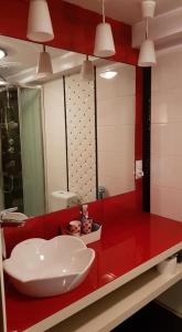 La salle de bains est pourvue d'un comptoir rouge et d'un lavabo. dans l'établissement Wiolinkowo, à Sarnaki