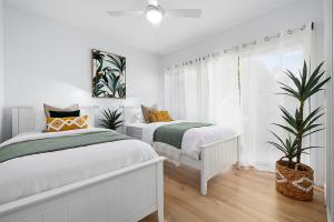 a white bedroom with two beds and a window at Papillon Coolum in Coolum Beach +21 photos