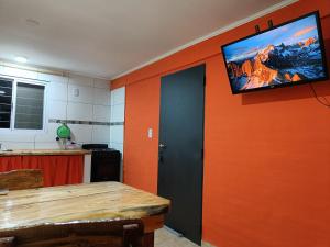 cocina con pared de color naranja y TV de pantalla plana en Rayo Solar Depto Rama Caída, en San Rafael
