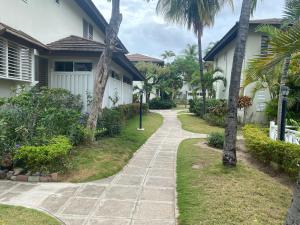a walkway in front of a house with palm trees at Finest Accommodation Renfrew Place 4-12 Renfrew Rd 2 bedroom 2 bat Apt # 15 New Kinston Jamaica in Kingston