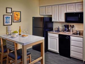 a kitchen with a table and a black refrigerator at Sonesta ES Suites Cincinnati - Sharonville East in Sharonville