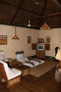 - un salon avec un lit, un canapé et une télévision dans l'établissement Les bungalows d'Ambonara, à Hell-Ville