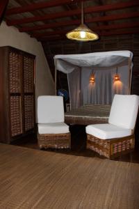 two white chairs and a bed in a room at Les bungalows d'Ambonara in Hell-Ville