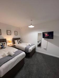 a hotel room with two beds and a flat screen tv at Bridge Place - Spacious home with plenty of beds! in Merthyr Tydfil