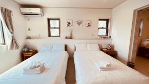 dwa łóżka w pokoju z białą pościelą i ręcznikami w obiekcie BlueOcean恩納村 w mieście Inbu