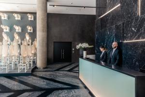 two people standing at a counter in a lobby with a wall of art at SLS Buenos Aires Puerto Madero in Buenos Aires