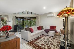 een woonkamer met een witte bank en rode kussens bij Villa 3 By The Sea in Coffs Harbour