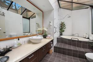 a bathroom with a tub and a sink and a tub and a mirror at Villa 3 By The Sea in Coffs Harbour