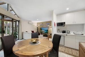 a kitchen and dining room with a wooden table and chairs at Villa 3 By The Sea in Coffs Harbour
