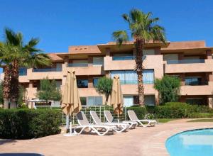 a hotel with chairs and umbrellas next to a pool at Luxury apartment Prestigia in Marrakesh