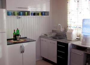 una cocina con armarios blancos y 2 botellas en una encimera en Casa de Ferias Alternativa, en Urubici