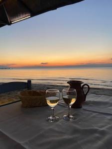 two glasses of white wine sitting on a table with the beach at Apartman Perea in Perea