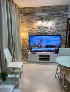 a living room with a flat screen tv on a brick wall at Apartman Perea in Perea