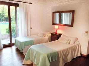 two beds in a room with a mirror and a window at Posada del Huerto in La Carrodilla