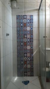 a bathroom with a shower with a tile wall at Hospedaria Ilhéus 04 in Ilhéus