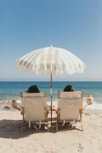two people sitting in chairs under an umbrella on the beach at Calamigos Guest Ranch and Beach Club in Malibu
