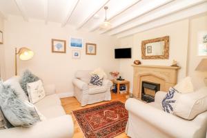 a living room with white furniture and a fireplace at The Shell Seekers in Fowey