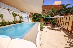 a swimming pool with chairs and an umbrella on a building at Casa Saab in Playa del Carmen