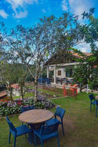 una mesa de madera y sillas en un patio con flores en Le Rêve Pousada e Restaurante en Guaramiranga