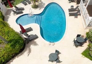 una vista sul tetto di una piscina con tavoli e sedie di Private Condo on the West Coast of Barbados a Saint James