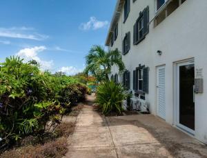セント・ジェームスにあるPrivate Condo on the West Coast of Barbadosのヤシの木が立ち並ぶ白い建物の横の歩道