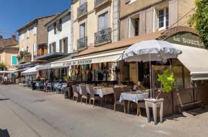 an outdoor restaurant with tables and chairs and umbrellas at Douceur sur la Sorgue in LʼIsle-sur-la-Sorgue